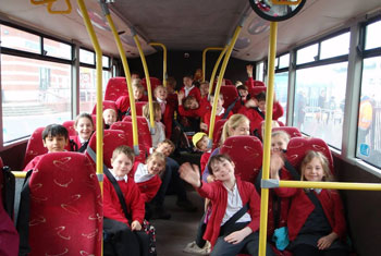 Picture of school children smiling on a coach journey to their school trip