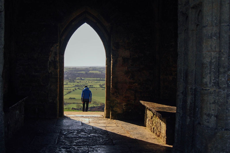 Photo of young person standing in silhouette in a church doorway