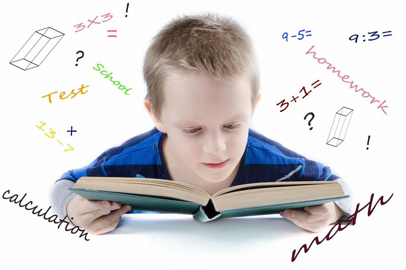 School boy reading book with maths symbols to reference mathematics themed school trips
